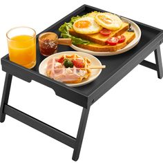 a tray with two plates of food on it and a glass of orange juice next to it