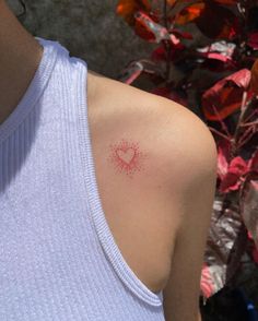 a person with a heart tattoo on their left shoulder and chest, next to some flowers