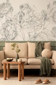 Living room with a large floral wall mural in soft monochromatic tones, a beige sofa, wooden table, and cozy decor accents, creating a warm and sophisticated atmosphere. Indoor Roses, Floral Wall Mural, Roses Wallpaper, Cosy Living, Rose Wallpaper, Blank Walls