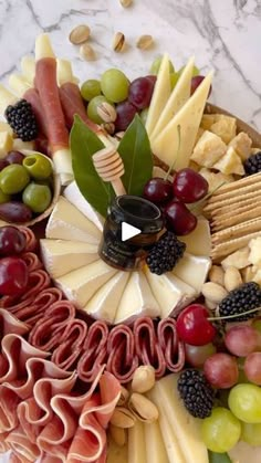 a platter filled with cheese, meats and fruit on top of a marble table