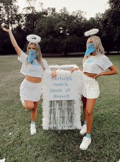 two women in matching outfits stand next to a sign that reads, watch made it heaven