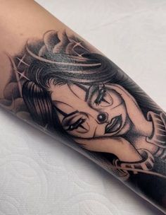 a woman's arm with a black and white tattoo design on her left arm