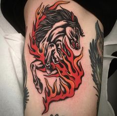 a woman's thigh with a horse and flames tattoo design on it, while she is wearing a black t - shirt