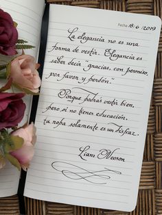 an open notebook with writing on it next to flowers