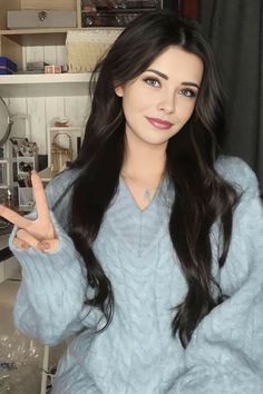 a woman with long black hair is making the peace sign