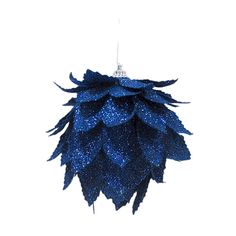 a blue christmas ornament hanging on a white wall in the shape of a pine cone