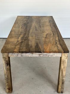 a wooden table sitting on top of a cement floor next to a white garage door