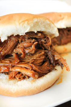 two pulled pork sandwiches sitting on top of a white plate