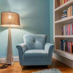 a light blue chair sitting in front of a book shelf filled with lots of books