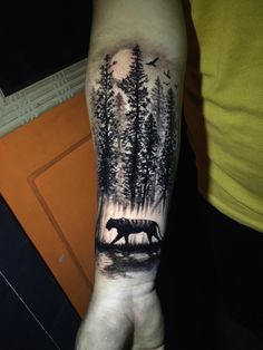 a man's arm with a bear and trees on it