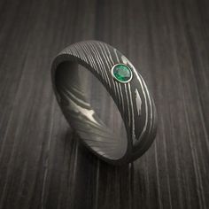 a ring with a green stone in the center on a wooden surface, close up