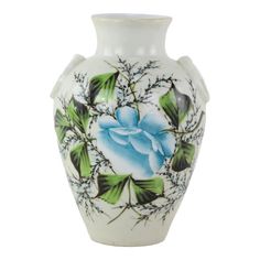 a white vase with blue flowers and leaves painted on the front, sitting against a white background