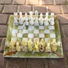 a glass chess board sitting on top of a brick floor covered in white and yellow pieces