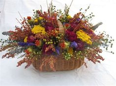 a basket filled with lots of colorful flowers on top of a white cloth covered table