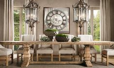 a dining room table with chairs around it and a large clock on the wall behind it