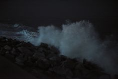 the waves are crashing against the rocks at night