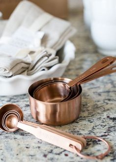 two measuring cups and spoons sitting on a counter top next to folded napkins