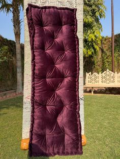 a large purple blanket sitting on top of a lush green field next to a palm tree