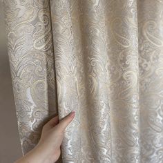 a hand is pulling up the curtain with their thumb