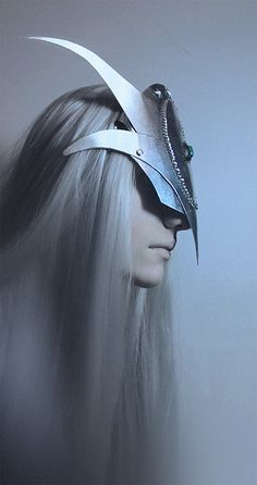 a woman with long hair wearing a helmet and metal scissors on her head, in front of a gray background