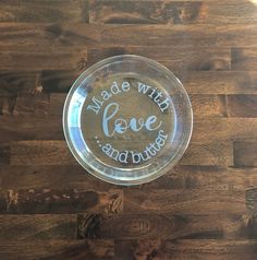 a glass plate with the words made with love and buttons on it sitting on a wooden table