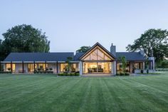 a large house with lots of windows and grass in the front yard at night time