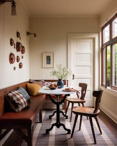 a table with two chairs and a bench in front of a window next to a door