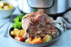 a plate with meat, potatoes and carrots in front of an instant pot