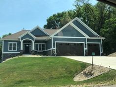 a large house with two garages and lots of green grass in front of it