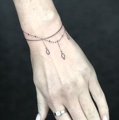 a woman's hand with a tattoo on it and a chain around the wrist