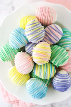 a white bowl filled with colorful candy covered in icing on top of a table