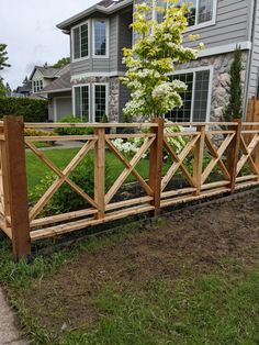 a wooden fence in front of a house with flowers growing on the top and bottom