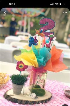 a vase filled with colorful flowers sitting on top of a pink tablecloth covered table