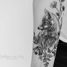 a black and white photo of a fox with flowers on it's arm,