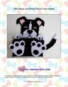 a crocheted black and white dog with paw prints on it's chest