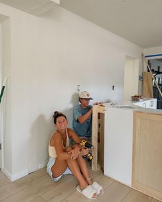 a man and woman sitting on the floor next to each other in a room under construction