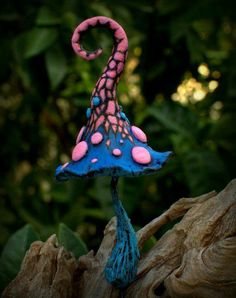 a blue and pink mushroom sitting on top of a tree stump