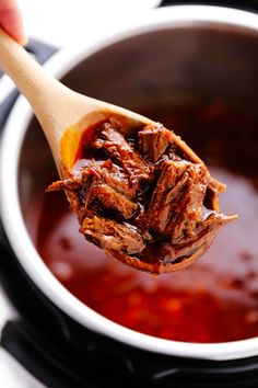 a wooden spoon full of pulled pork with bbq sauce