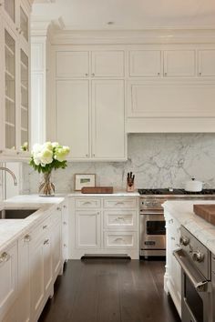 a large kitchen with white cabinets and marble counter tops, along with wooden flooring