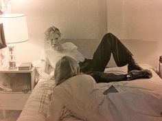 an old photo of two people laying on a bed in a room with a lamp