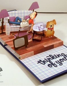 a pop up card with a man laying on a couch next to a dog and tv