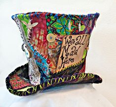 a decorative hat made out of fabric with words and pictures on the front, sitting on top of a pillow