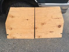 two pieces of wood sitting on the ground next to a truck's tire compartment