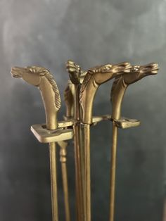 three brass horse head candlesticks are on display in front of a gray background