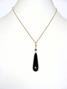 This simple yet dramatic necklace can take you day to night in style...a slim, golden rolo chain supports an elongated, smooth teardrop of black onyx with a sapphire accent. The onyx is measures 33mm long by 10mm wide and it is half-drilled which gives it a polished look. A smooth sapphire rondelle and small corrugated golden bead finish the drop, it hangs on a tiny ring allowing it to move on the chain...the drop measures just over 2 inches. The chain adjusts from 15.5 to 17.75 inches, the end of the extension chain is decorated with a second sapphire. All metal is goldfill.  Summary: Stones:  black onyx, sapphire Metal:  goldfill Length:  15.5-17.75 plus 2 1/8" drop Clasp:  lobster claw 👉 Your purchase will ship within 24 hrs. 👉 Domestic shipping includes tracking Welcome to my shop: h Dramatic Necklace, Tiny Rings, Y Necklace, Teardrop Pendant, Rolo Chain, Move On, Night In, Black Onyx, Lobster Claw