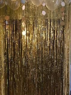 a room filled with lots of balloons and gold foil curtain curtains hanging from the ceiling