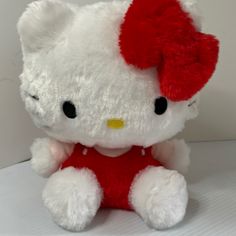 a white hello kitty stuffed animal with a red bow on it's head and chest