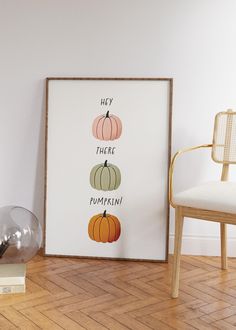 there are three pumpkins on the floor next to a chair and a framed poster