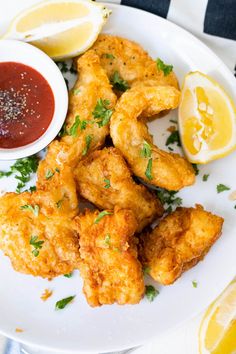 fried food on a white plate with lemons and ketchup