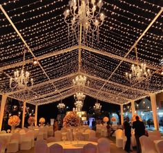 the inside of a wedding reception with chandeliers and white linens on the ceiling